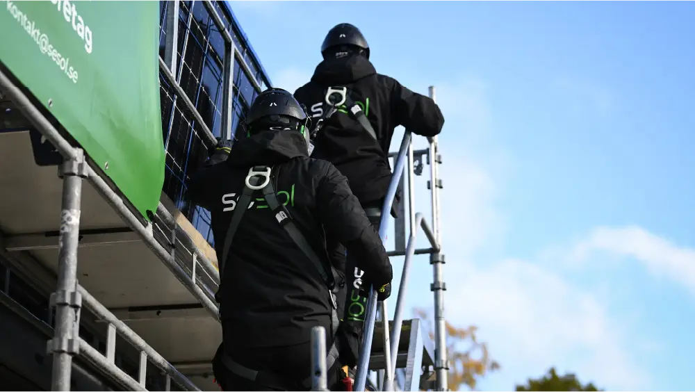 Montörer klättrar upp för ställning vid solcellsmontage