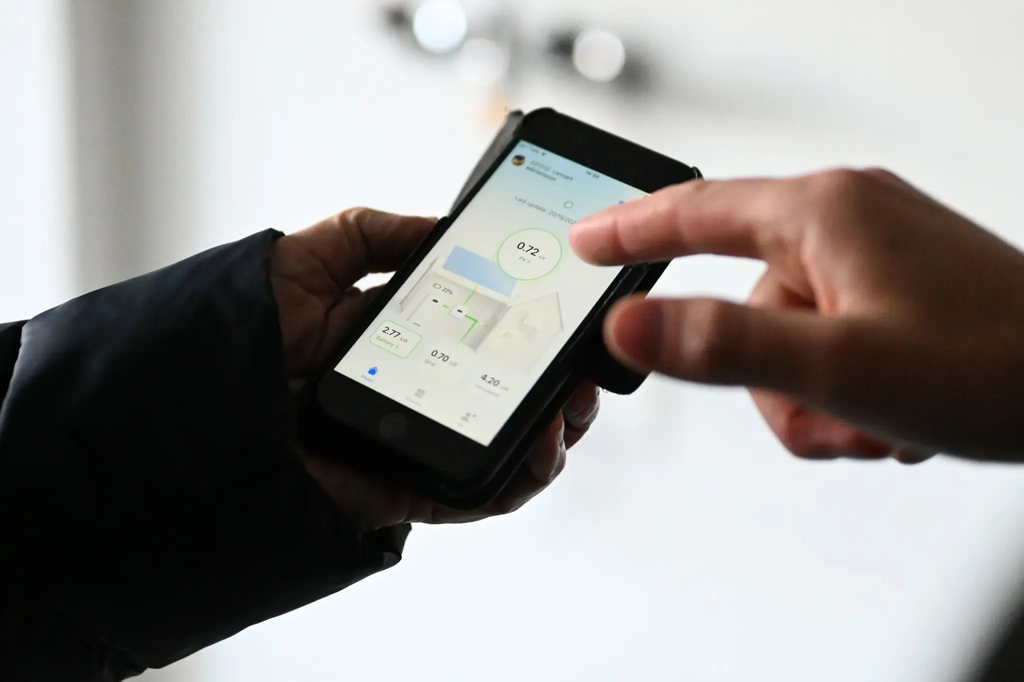 Person håller i telefon med app som kan styra och följa upp solcellsproduktion