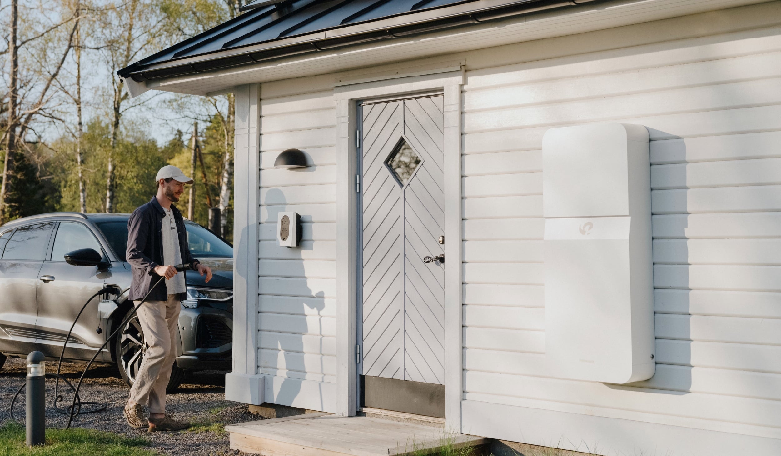 Vitt Polarium Home batteri på vit fasad med männsika i bild